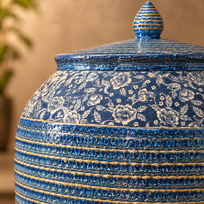 Close-up of a handcrafted blue floral ceramic decorative storage jar showcasing intricate floral detailing and textured glazed finish.