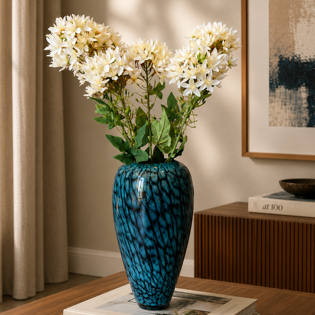 Elegant blue textured glass vase with white floral arrangement styled on a wooden coffee table in a modern luxury living room setting.