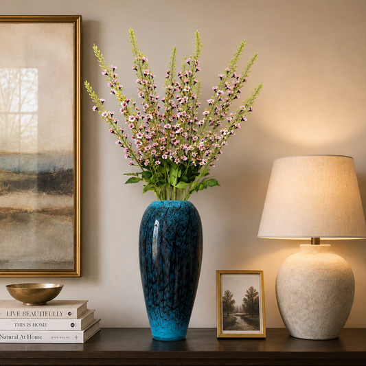 Blue marbled ceramic floor vase with delicate pink flowering stems displayed on a dark wood console table against a neutral wall in an elegant modern living room.