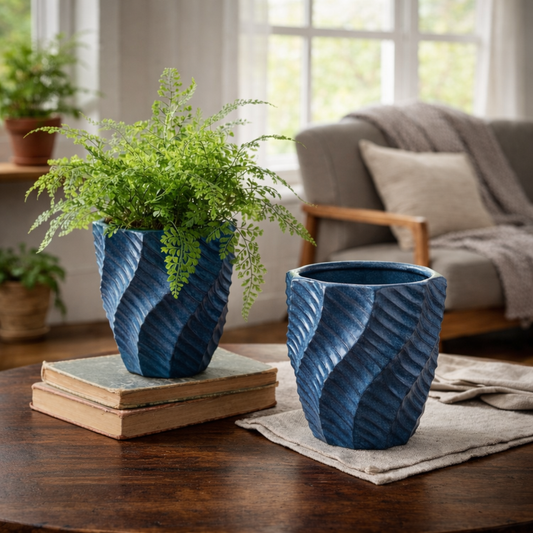 Blue textured ceramic planters displayed on a dark wood coffee table with a lush green fern in one planter, styled in a bright living room with natural light.