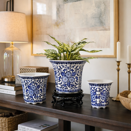 Blue and white floral ceramic planter set displayed on a wooden console table with indoor plant and decorative home accents.