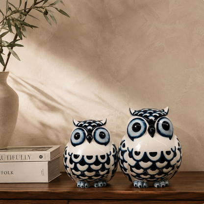 Blue and white ceramic owl figurines displayed on a premium walnut console table with luxury coffee table books, an elegant ceramic vase, and an olive branch against a warm beige Venetian plaster wall. Perfect decorative owl sculptures for sophisticated home décor.