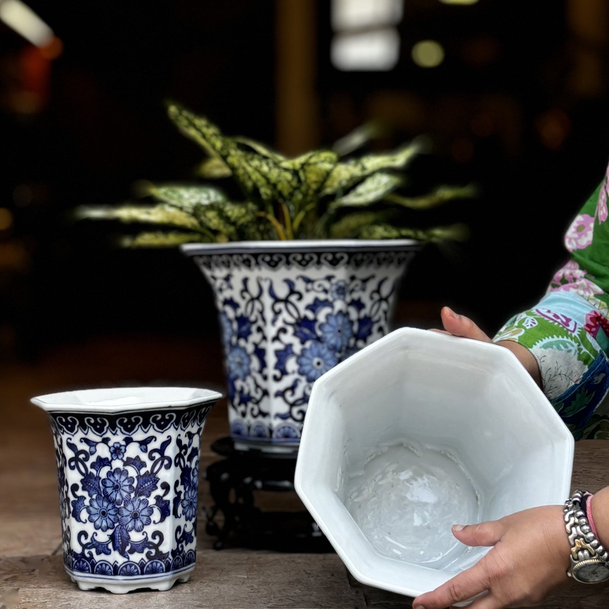 Hand-painted blue and white ceramic planter showing interior and drainage hole with matching floral planter set.