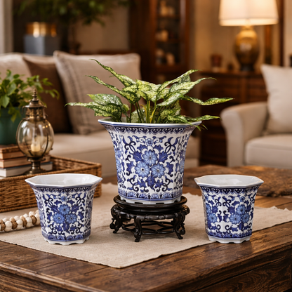 Hand-painted blue and white ceramic planter set with indoor foliage arranged on a rustic coffee table in a living room.