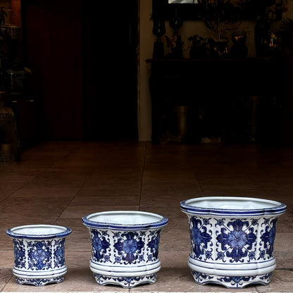 Set of three blue and white hand-painted ceramic floral planters in different sizes displayed on a tabletop, showcasing intricate traditional patterns.