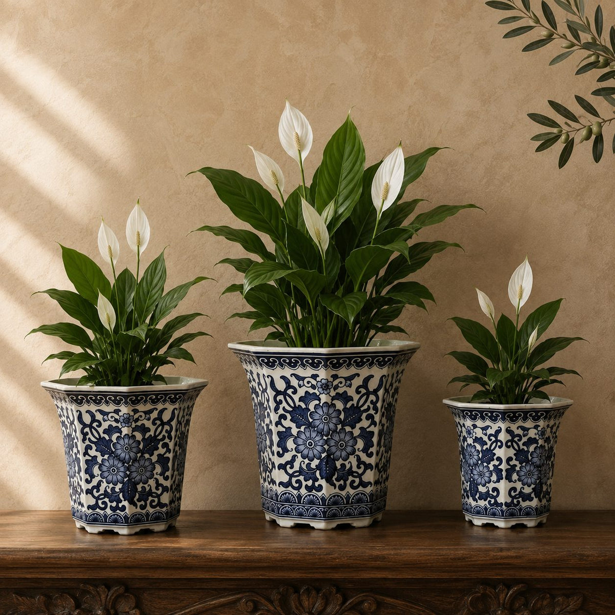 Blue and white hand-painted porcelain planter set displayed with lush Peace Lily plants on a carved wooden console in a luxury home interior.