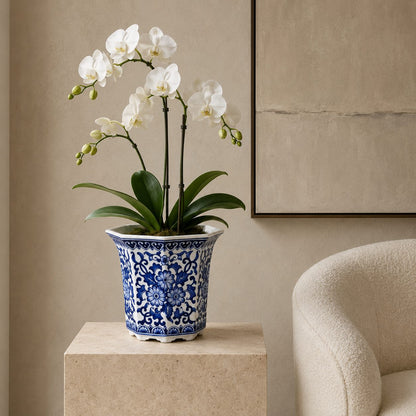 Blue and white floral porcelain planter styled with a white orchid on a stone pedestal in a modern luxury living room.