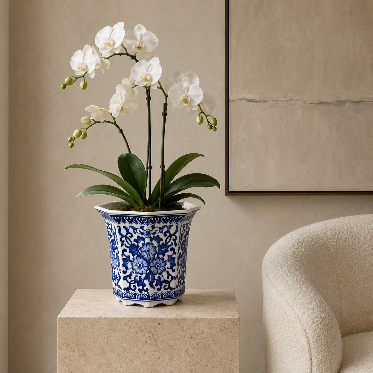 Blue and white floral porcelain planter styled with a white orchid on a stone pedestal in a modern luxury living room.