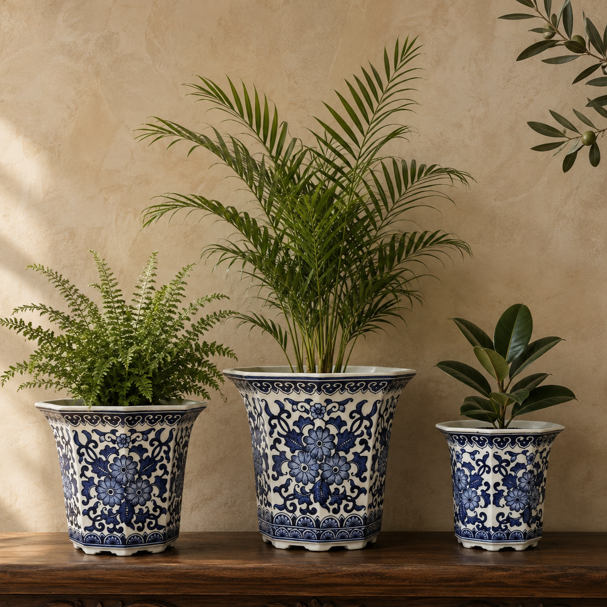 Blue and white octagonal ceramic planters styled on a luxury wooden console with a live fern, palm, and rubber plant against a warm beige Venetian plaster wall, creating an elegant home décor display.