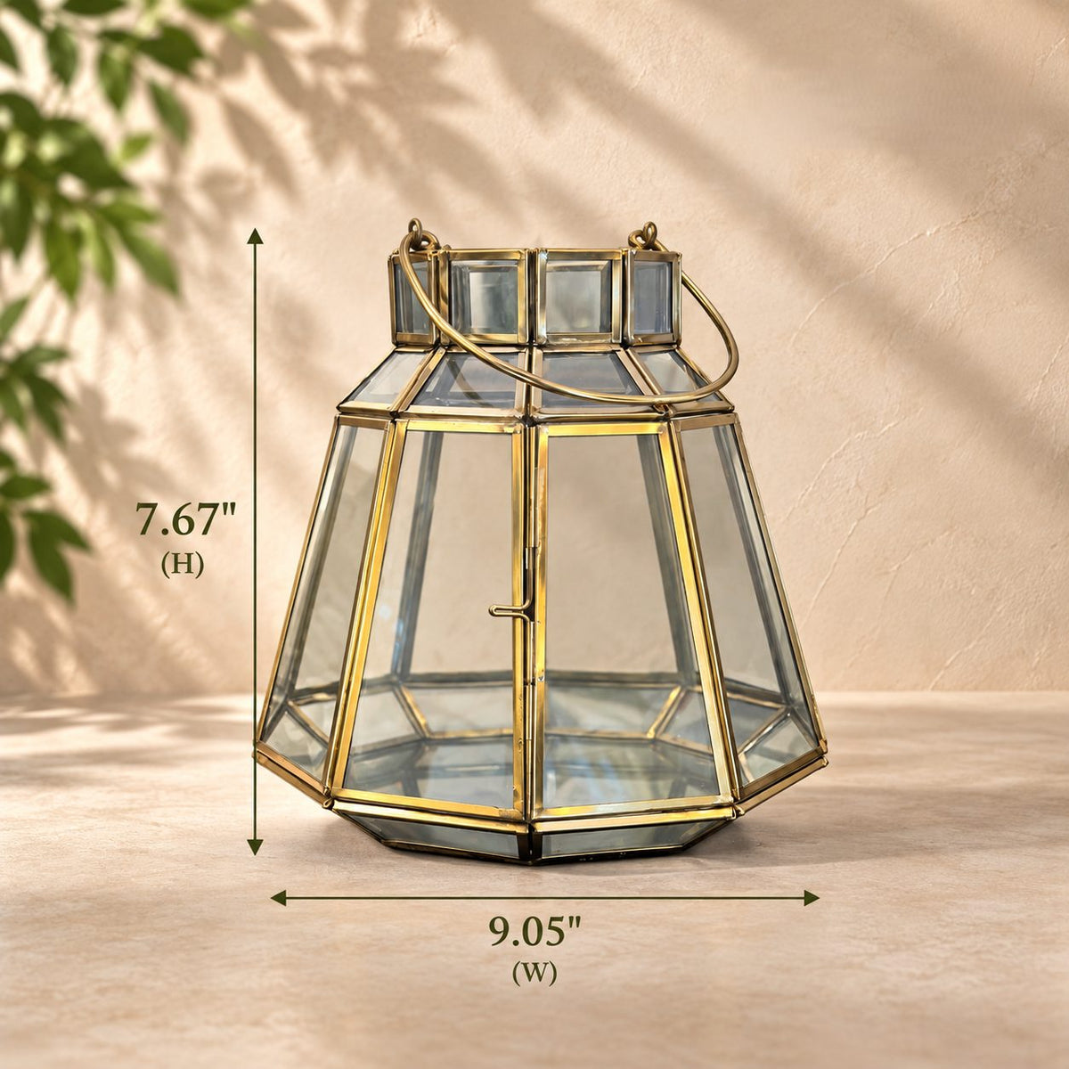 Handcrafted brass and clear glass geometric lantern with dimensions displayed, measuring 7.67 inches in height and 9.05 inches in width, suitable for indoor and sheltered outdoor décor.