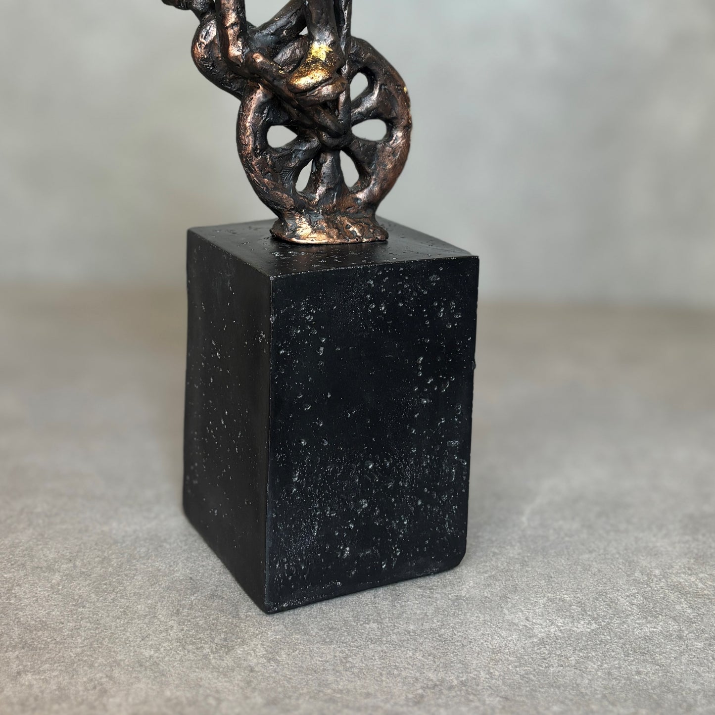 Close-up of a rustic bronze-finished biker figurine mounted on a solid matte black rectangular pedestal base with textured detailing.