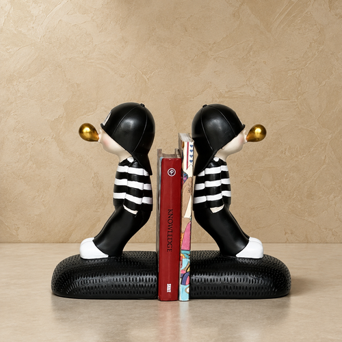 Boy blowing bookend, black and white resin, on beige studio backdrop