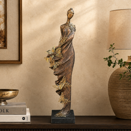 Luxury lady butterfly sculpture styled on a dark wooden console table in a premium living room with a warm beige Venetian plaster wall, showcasing elegant modern home décor by Inara Home Decor.