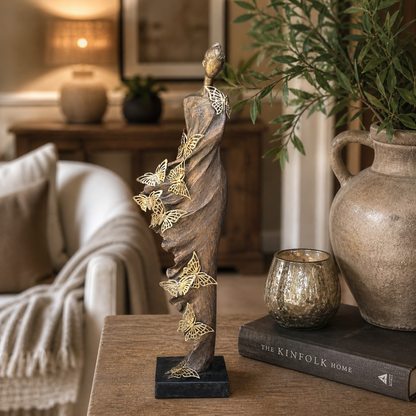 Elegant butterfly lady sculpture displayed on a wooden console table in a warm luxury living room setting with decorative accents and soft ambient lighting.