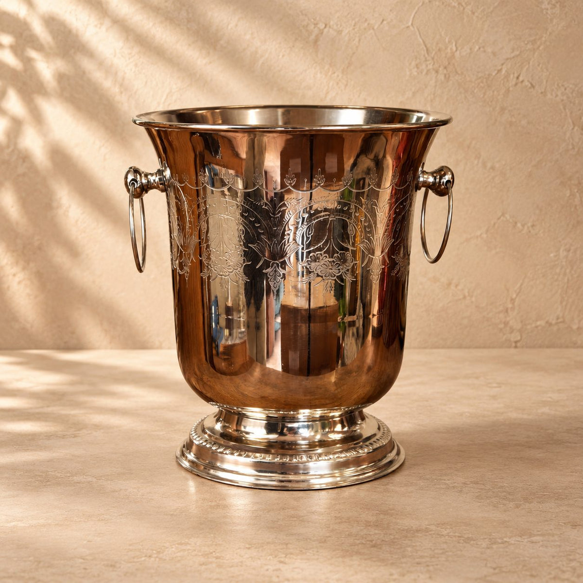 Classic stainless steel wine and champagne chiller with an engraved decorative finish on a premium luxury studio backdrop featuring a warm beige Venetian plaster wall and seamless matte microcement floor. Perfect for elegant home bars, dining tables, and luxury entertaining.