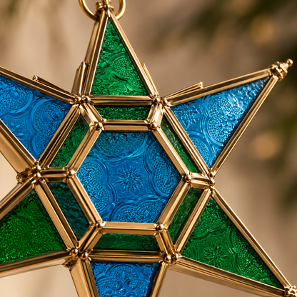 Close-up of handcrafted blue and green stained glass hanging star lantern featuring an elegant brass frame and intricate embossed glass detailing