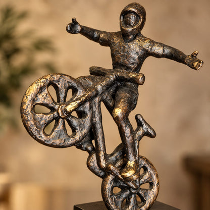 Close-up of premium resin cyclist balancing bike sculpture showcasing artistic craftsmanship, textured antique bronze finish and modern decorative design.