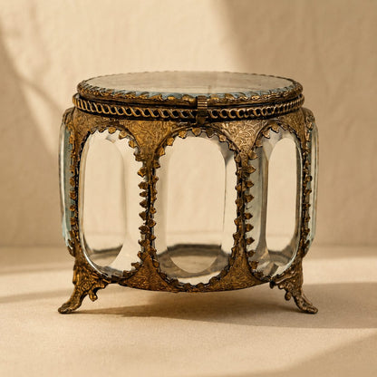 Close-up view of an antique brass and glass trinket box with handcrafted vintage detailing and beveled glass panels.