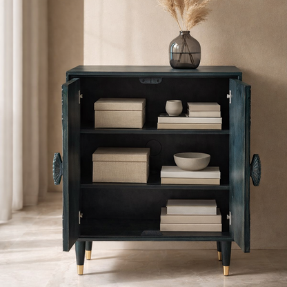 Distressed teal wooden sideboard cabinet with open doors styled with storage boxes, books, bowls, and decorative vase in a warm interior.