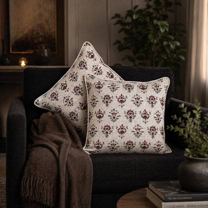 Floral block print cushion covers styled on a dark upholstered chair in a luxury living room, featuring beige fabric with burgundy floral motifs and elegant home decor accents by Inara Home Decor.