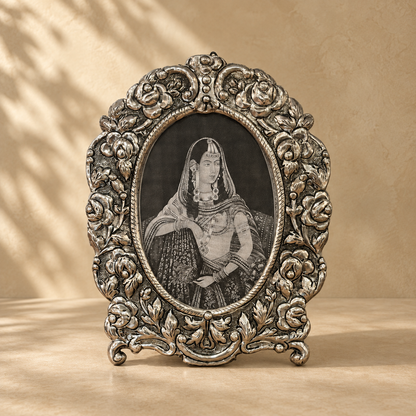 Florence Heirloom antique silver oval floral photo frame with intricate embossed detailing displayed against a warm neutral background.