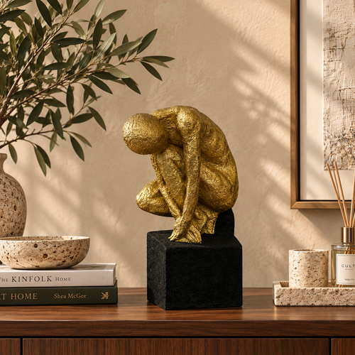 Modern gold abstract human sculpture styled on a walnut console in a luxury living room with premium contemporary décor.