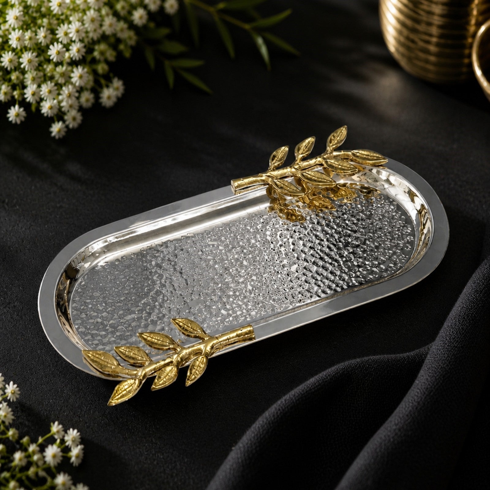 Luxury hammered silver serving tray with elegant gold leaf handles styled on a black tabletop with floral accents, perfect for modern table decor, serving essentials, and sophisticated home styling.