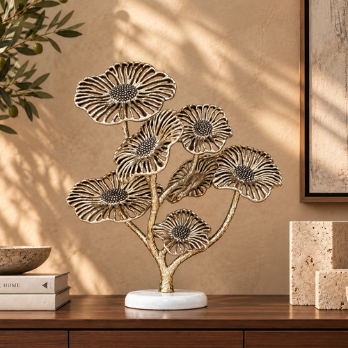 Gold metal floral sculpture with a white marble base styled on a dark walnut console table in a luxury living room featuring warm beige walls, olive branches, travertine décor, and soft natural sunlight.