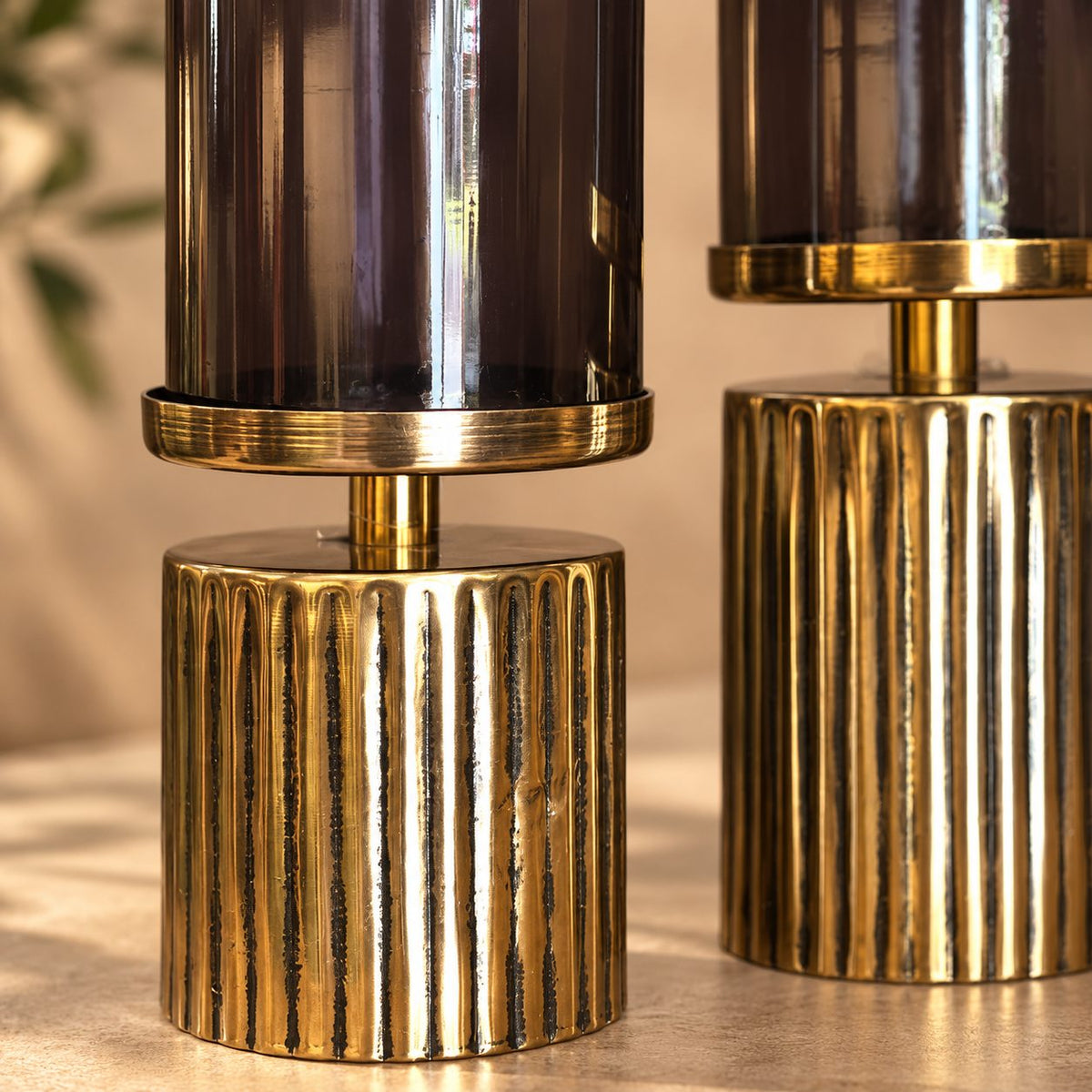 Close-up of the ribbed gold metal base and smoked glass hurricane shade showcasing premium craftsmanship.