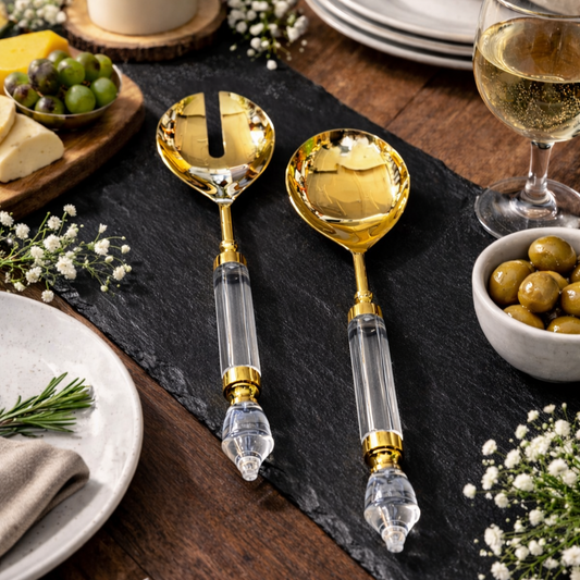 Luxury gold salad server set with clear acrylic handles styled on a rustic wooden dining table with olives, cheese, and wine, premium modern tableware décor