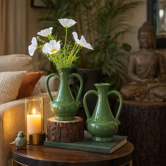 Set of glossy green ceramic vases with white flowers styled on a wooden side table in a cozy living room with candle and Buddha decor.