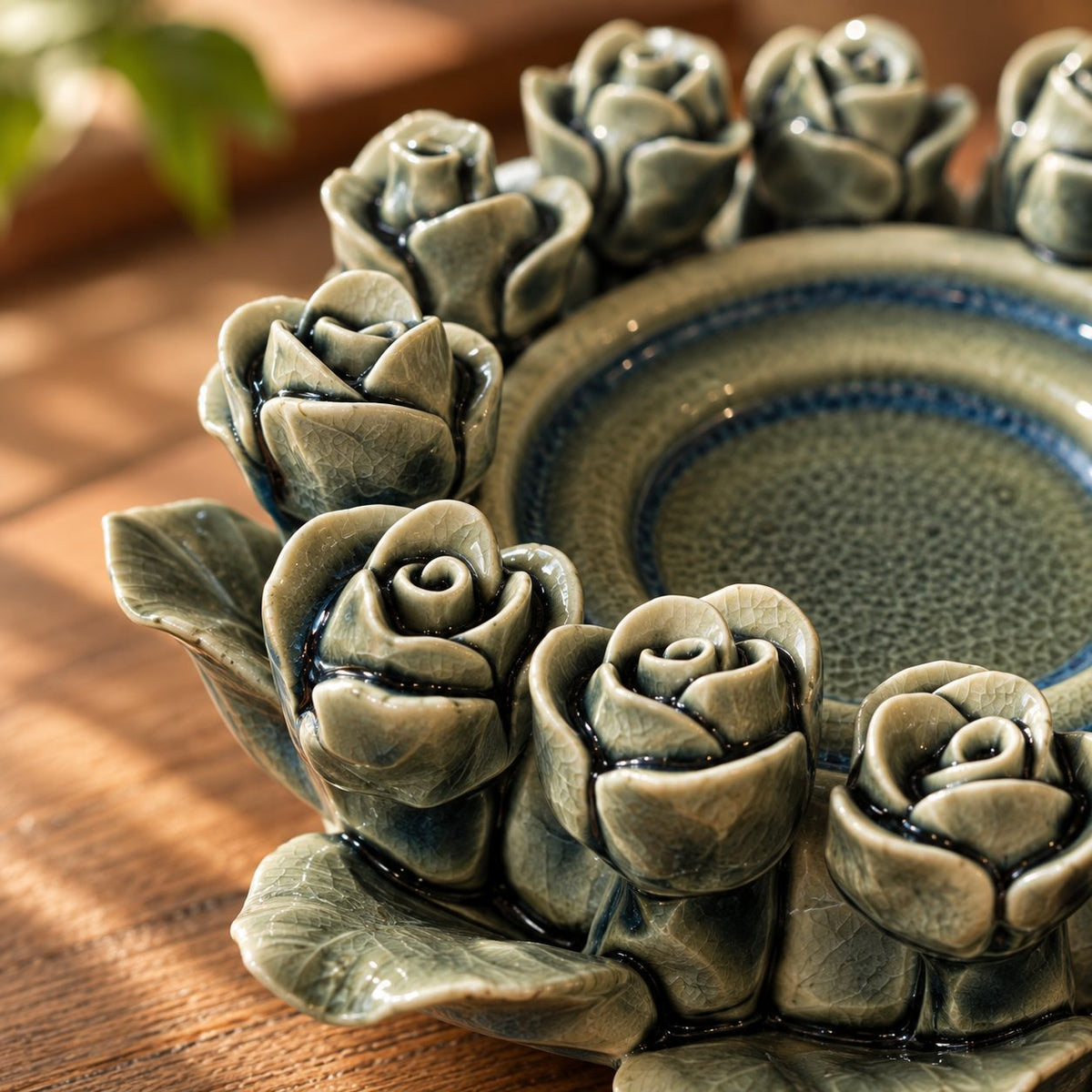 Close-up of the handcrafted rose detailing and glossy crackle glaze on a green ceramic tealight holder.