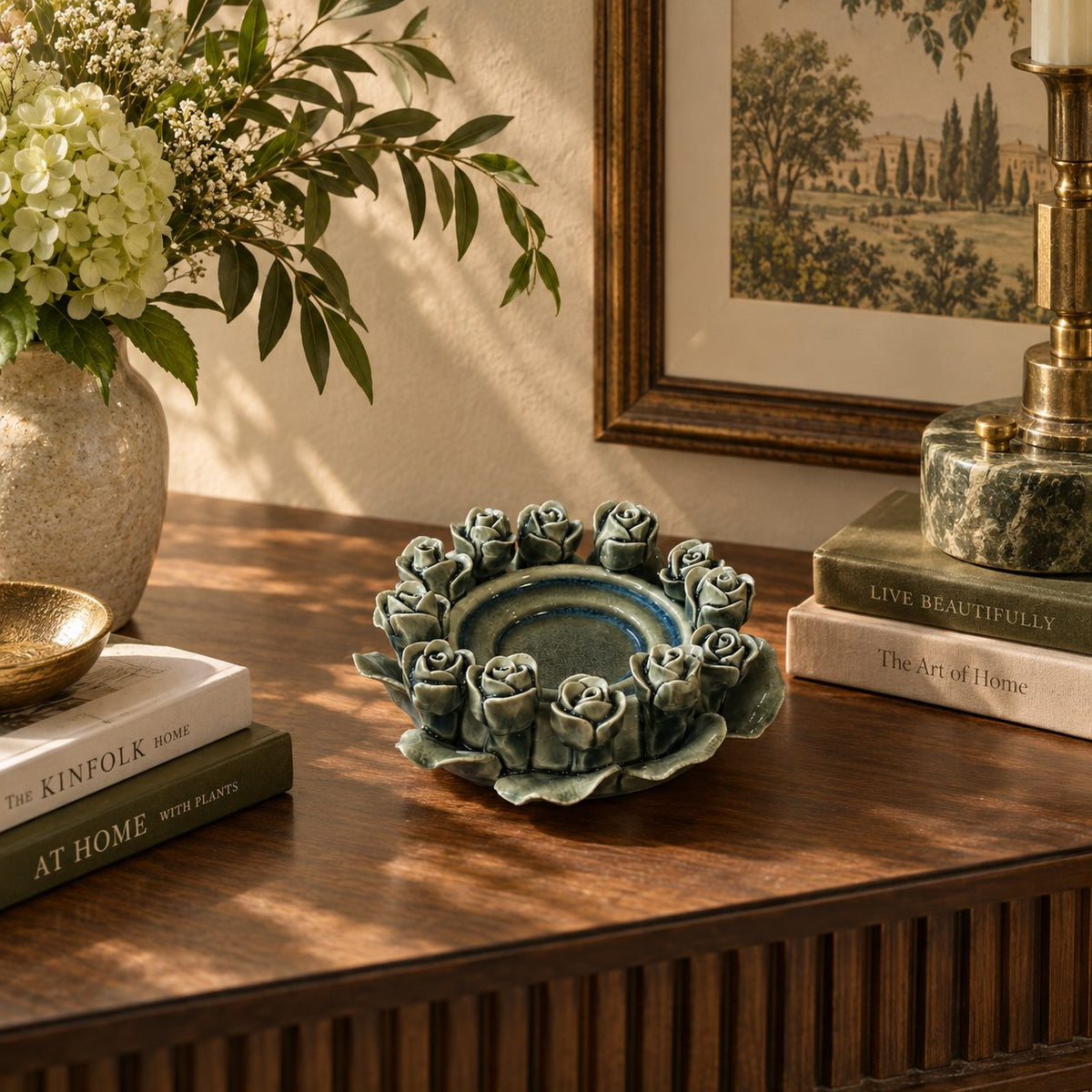 Handcrafted green ceramic rose tealight holder styled on a luxury console table with books, flowers, and decorative accents.