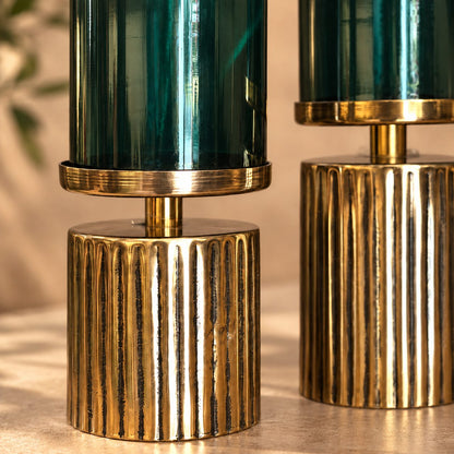 Close-up of Inara Home Decor Green Glass Hurricane Shade Set of 2 featuring emerald green glass cylinders with antique brass fluted metal bases, showcasing premium craftsmanship and luxury home décor styling.