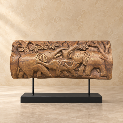 Hand-carved wooden elephant family decorative panel with detailed foliage on a black metal stand.