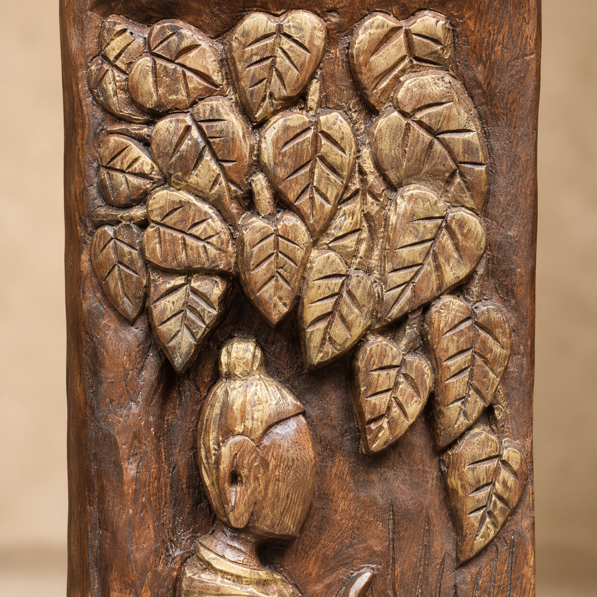Close-up of hand-carved wooden decorative sculpture with antique gold-toned leaf detailing and carved figure.