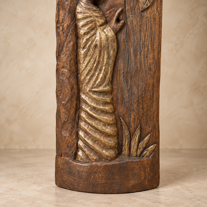 Close-up of hand-carved wooden sculpture showing antique gold-toned robe detailing, carved foliage and natural wood base.