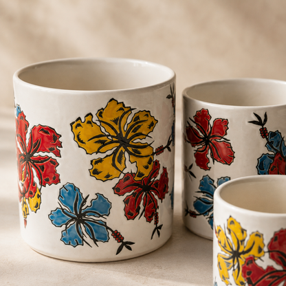Close-up of a hand-painted floral ceramic planter set of 3 featuring vibrant red, yellow, and blue hibiscus artwork on premium white ceramic decorative indoor plant pots.