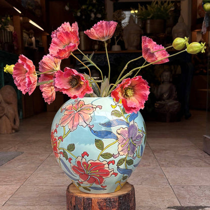 Close-up of a handcrafted ceramic jar with intricate floral artwork and red poppy flowers in an elegant indoor setting.