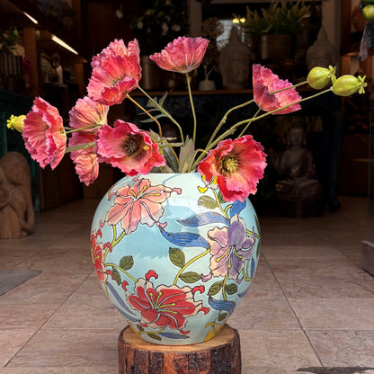 Close-up of a handcrafted ceramic jar with intricate floral artwork and red poppy flowers in an elegant indoor setting.