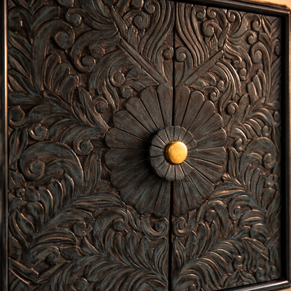 Close-up of handcarved floral pattern on dark teal wooden cabinet door with antique brass knob detailing.