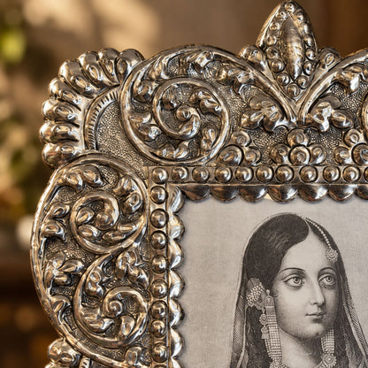 Close-up of the hand-embossed scrolls and beaded border on the antique silver photo frame.
