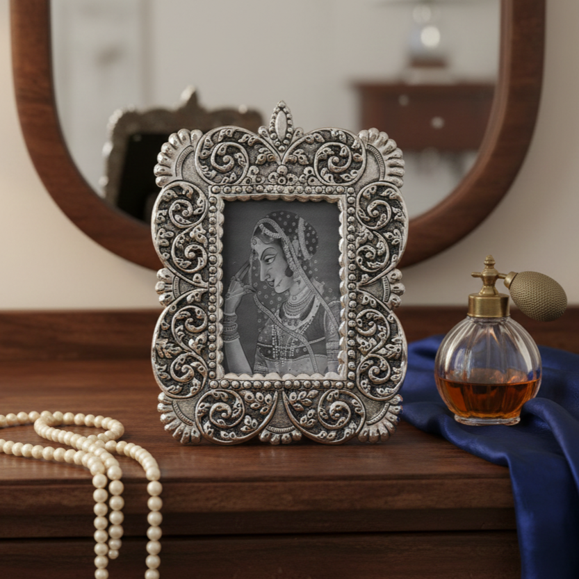 Handcrafted antique silver photo frame with intricate floral embossing placed on wooden dresser with vintage mirror and décor accents