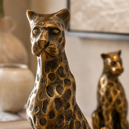 Close-up of a handcrafted brass leopard sculpture showcasing its detailed textured finish and artisanal craftsmanship, with the matching leopard sculpture softly blurred in the background.