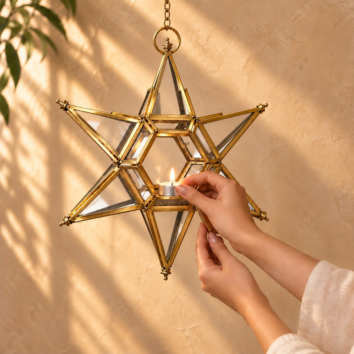Hand placing a tealight candle inside a handcrafted brass hanging star lantern with premium stained glass panels.
