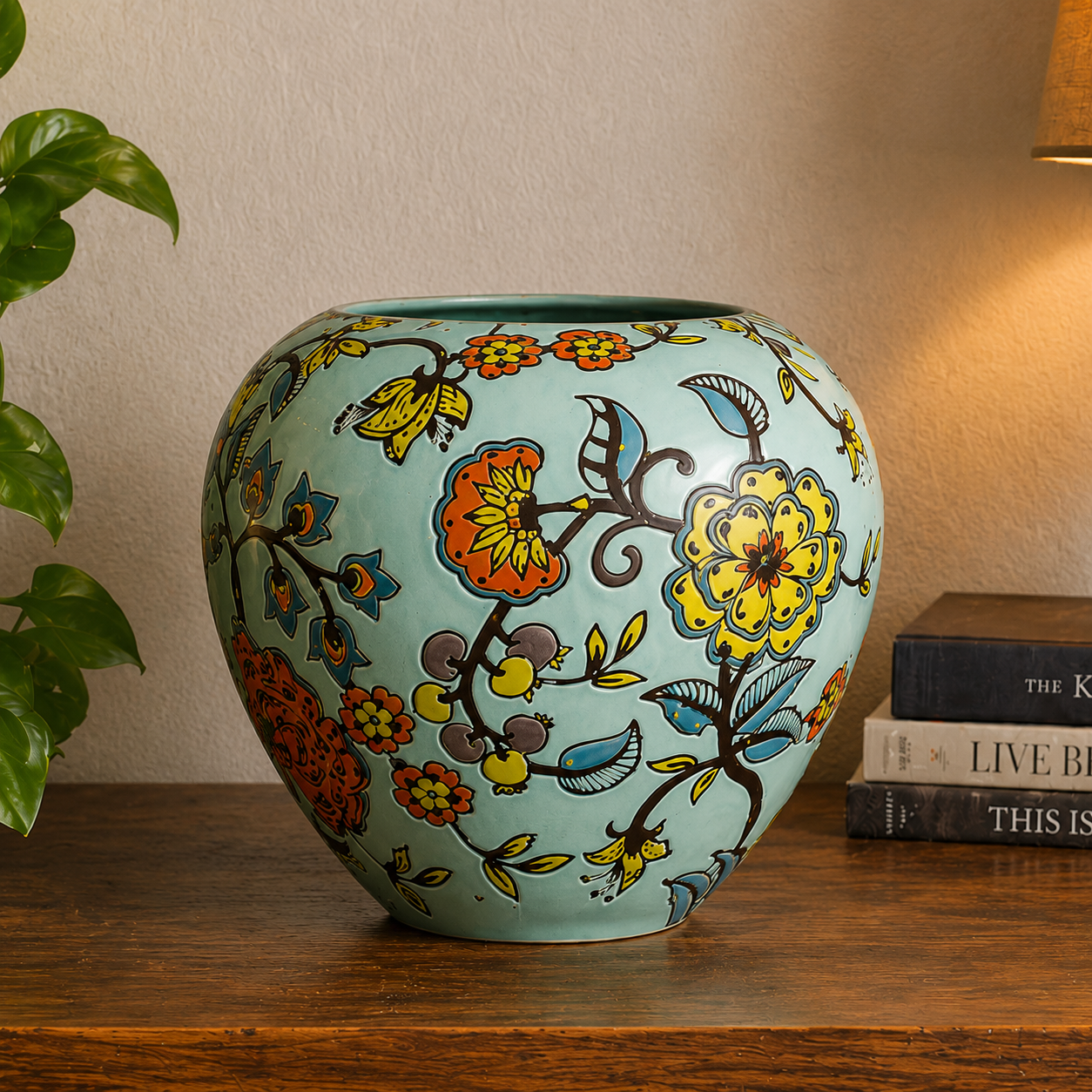 Close-up of a handpainted floral ceramic vase with intricate botanical patterns styled on a rustic wooden console table in a warm modern interior.