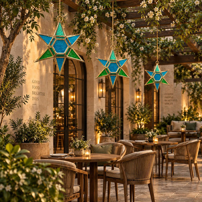 Blue and green stained glass hanging star lantern suspended beneath a luxury outdoor pergola in a premium patio setting, decorative handcrafted hanging lantern by Inara Home Decor.
