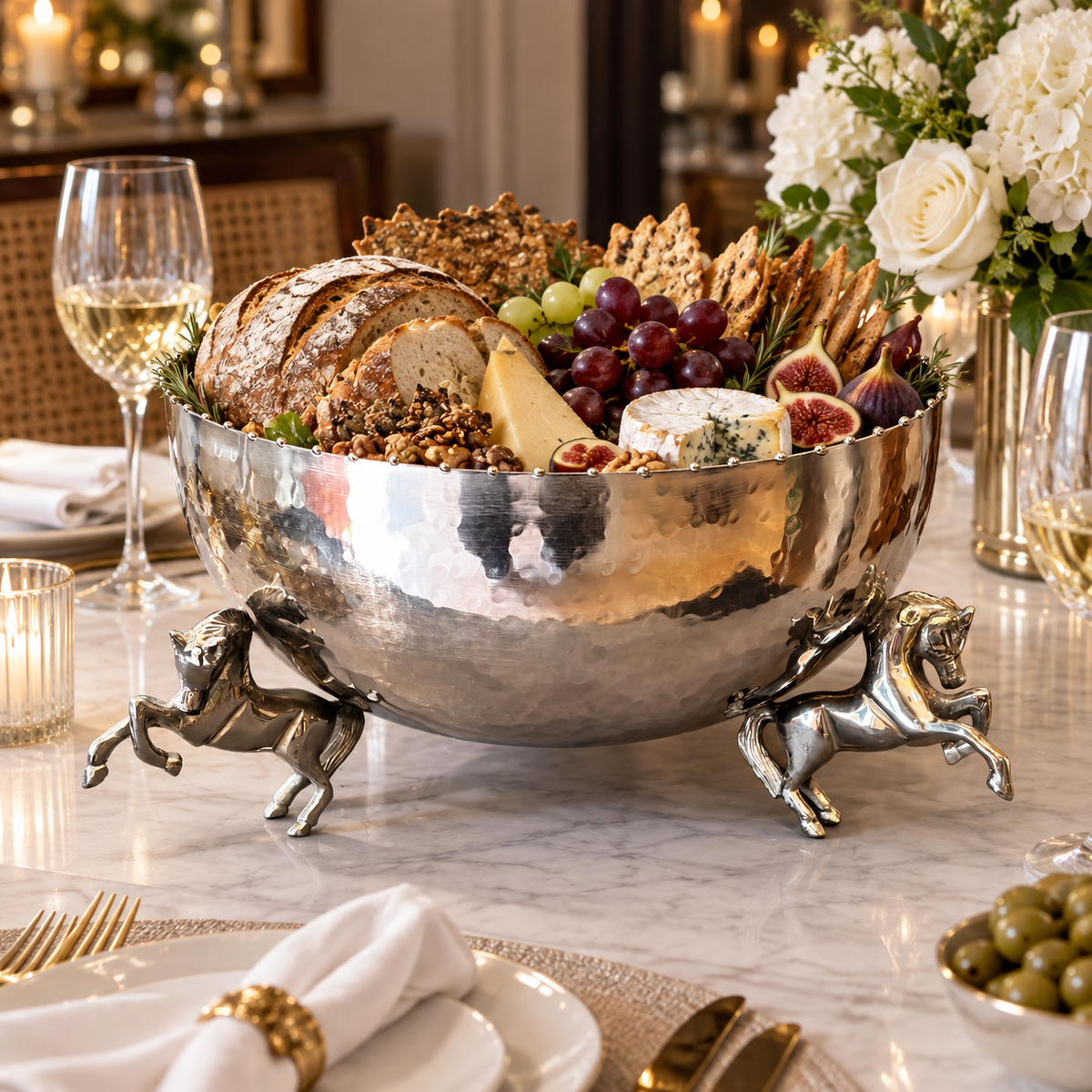 Luxury silver decorative horse leg bowl styled with artisan bread, cheese, grapes, crackers and figs as an elegant charcuterie centerpiece.