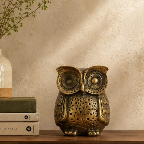 Antique brass owl figurine styled on a wooden console table with books and ceramic vase in a modern luxury home.