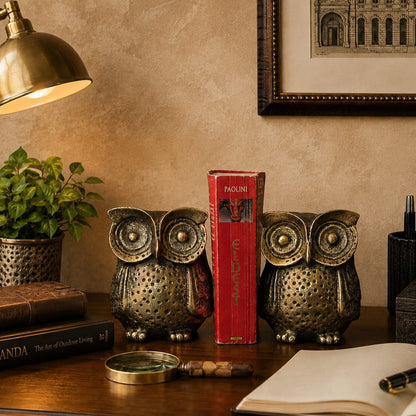 Antique brass owl bookends styled on a dark walnut desk with a red book, brass desk lamp, and luxury warm beige Venetian plaster wall backdrop in an elegant home study.